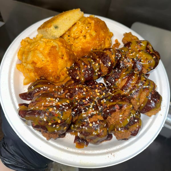Aljoom BBQ plate with saucy chicken, mac and cheese, and cornbread on a white plate.