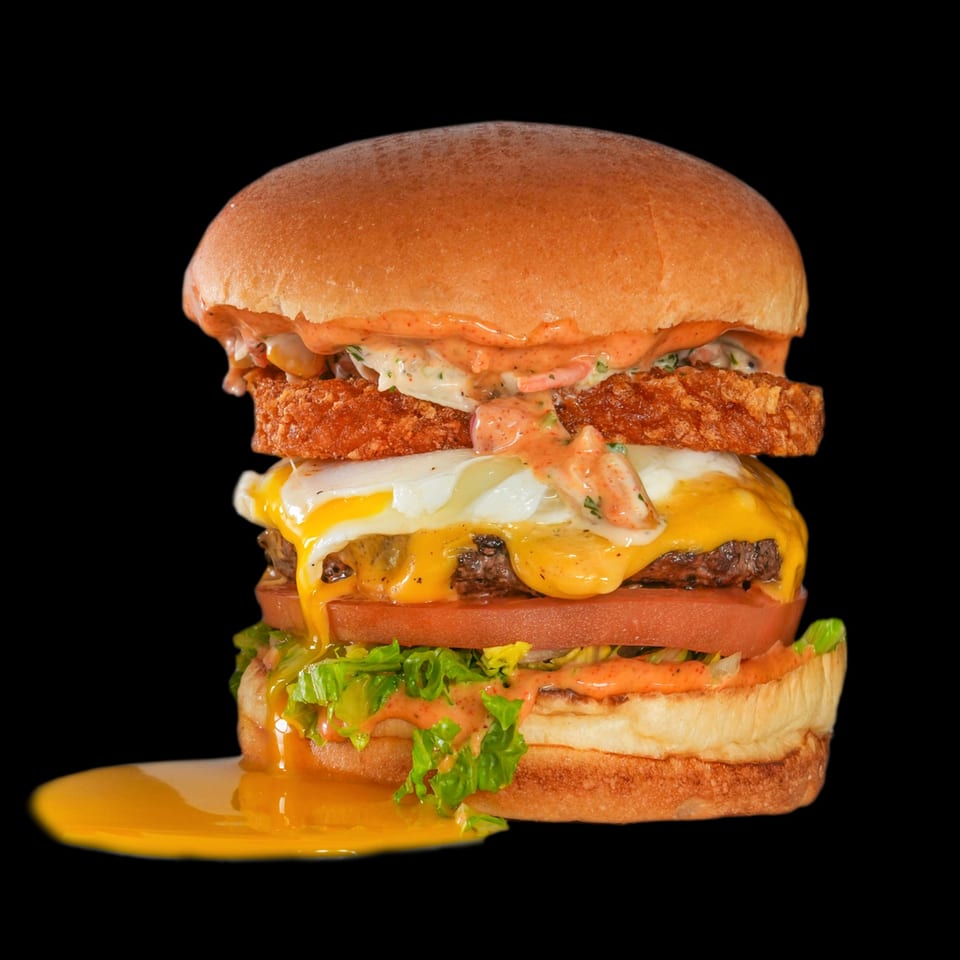 Aljoom BBQ's towering burger with a runny fried egg, hash brown, cheese, and fresh vegetables.